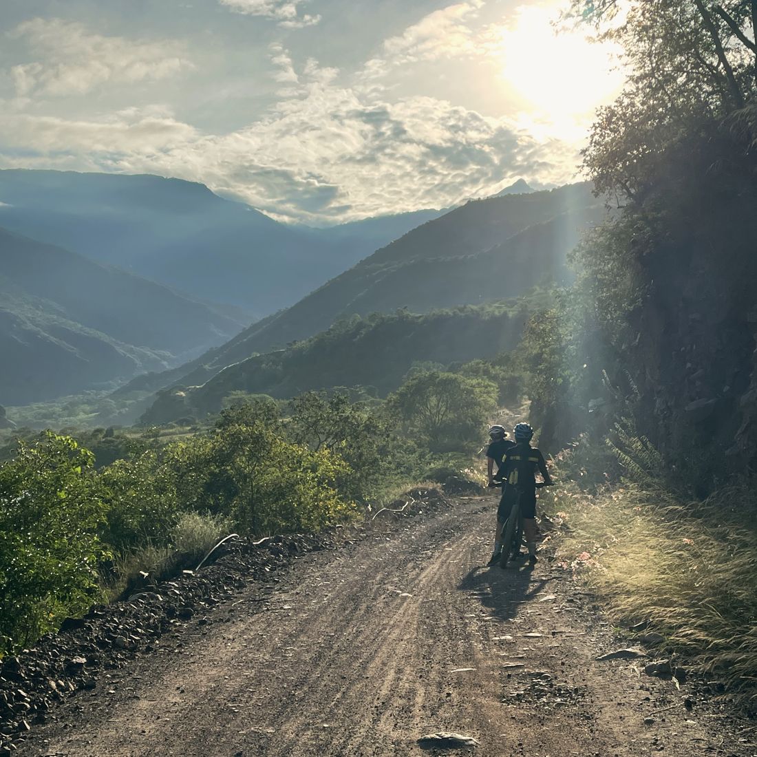 A rider on a dirt road with sunlight pouring into the canyon