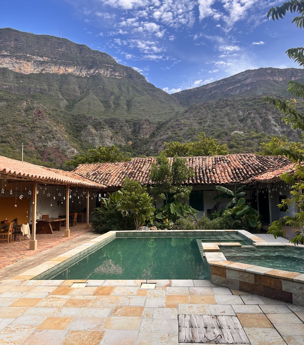 A courtyard pool and tiled roofs under the canyon walls in Jordán